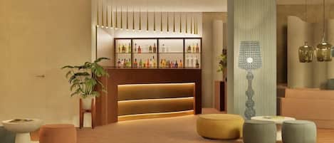 A modern lobby with a reception desk, seating area, and a bar with bottles.