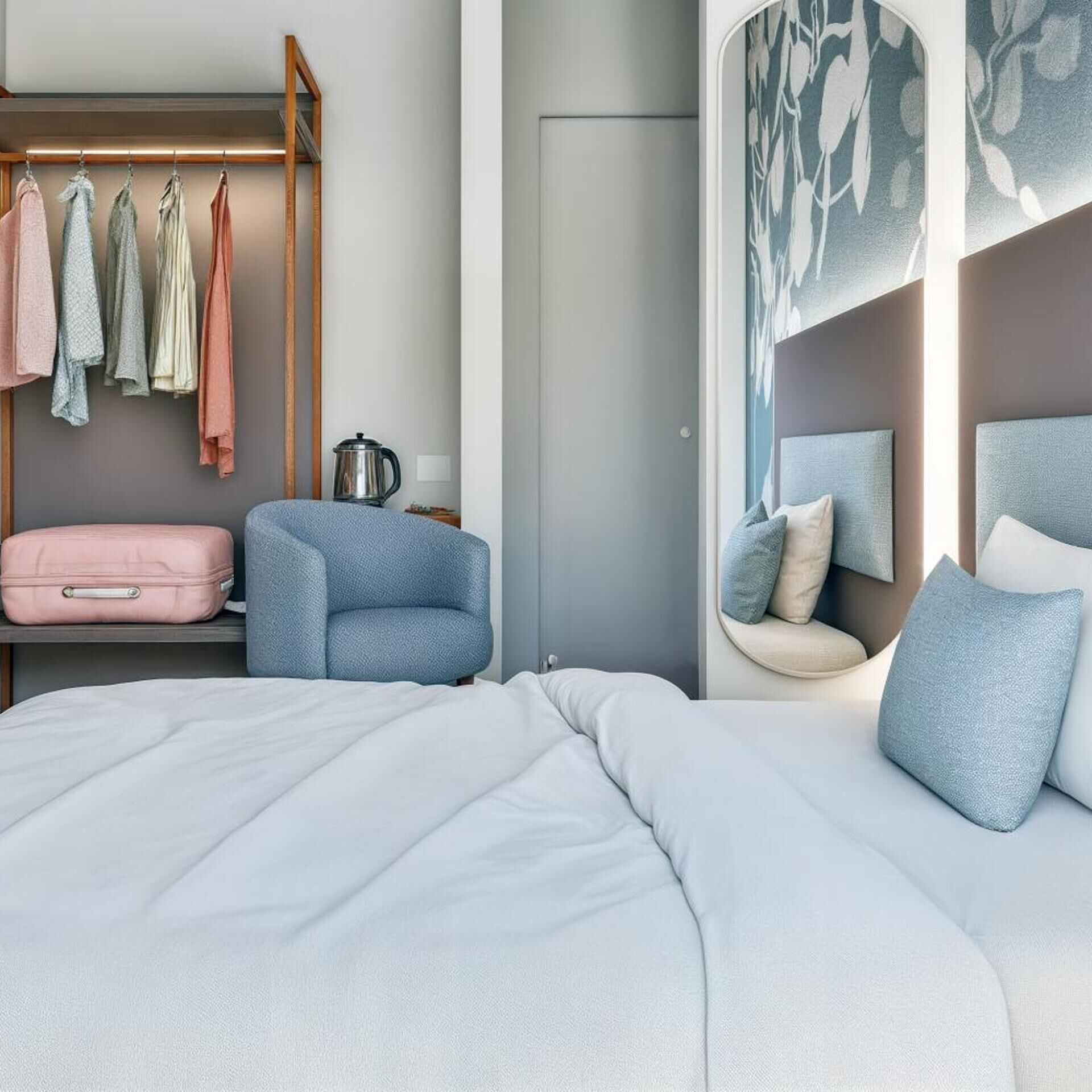 Une chambre à coucher avec un lit, un coin salon avec une table basse, une armoire avec des vêtements suspendus et une valise.