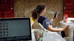 Una persona sentada a una mesa con una computadora portátil, una taza y un tarro de mantequilla de maní.