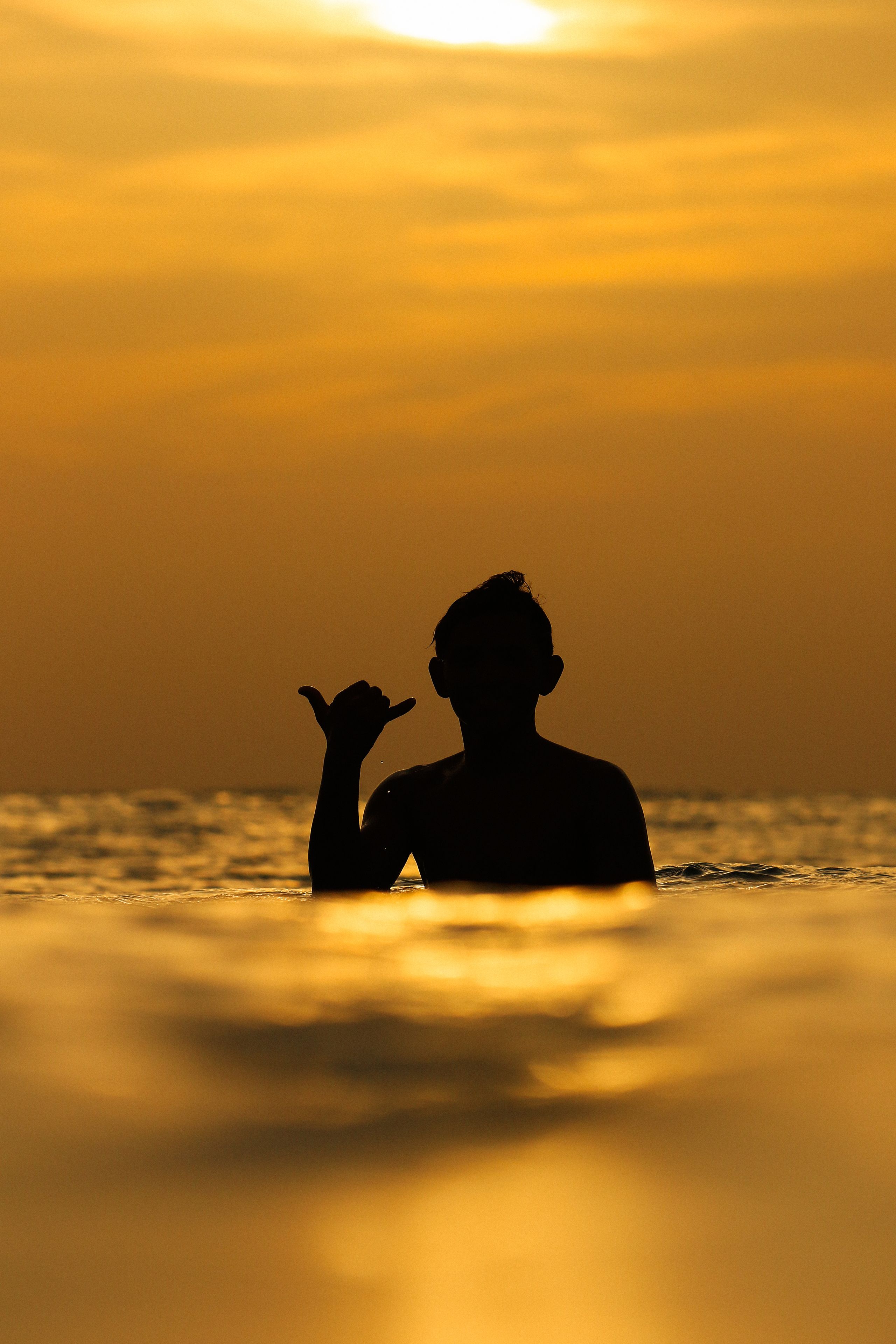 Silouette di una persona nell'acqua con un tramonto sullo sfondo.