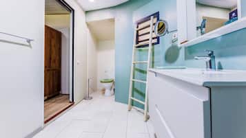 Un baño con inodoro, lavamanos, espejo y puerta de madera.