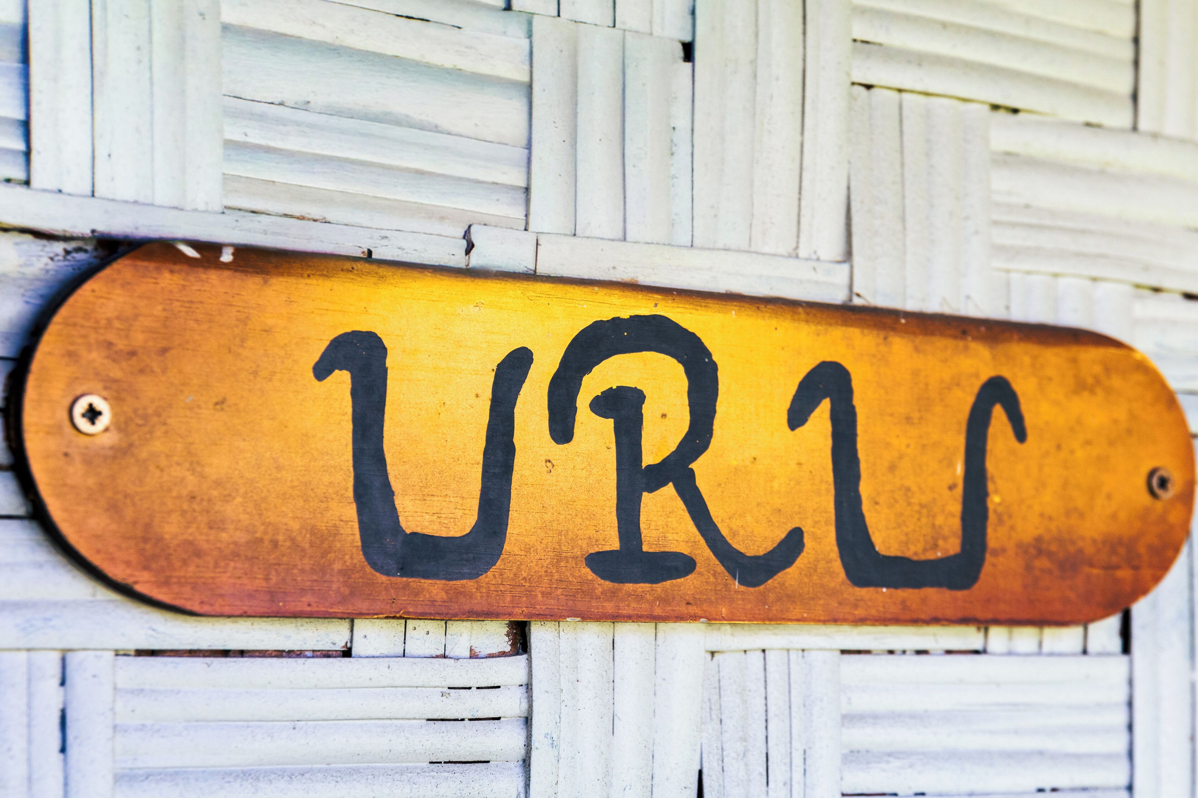 A wooden sign with the letters 'UR' painted in black.