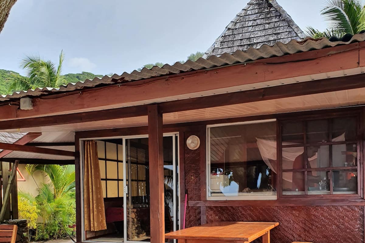 A wooden structure with a tiled roof, a wooden bench, and a table on a red deck.