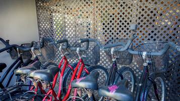 A row of bicycles with baskets, secured to a wall with a lattice pattern.