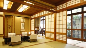 Una habitación tradicional japonesa con suelo de tatami, puertas correderas shoji y una zona de estar con esterillas de tatami.