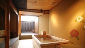 Un onsen japonés tradicional con interior y suelo de madera, y vistas a una valla de madera en el exterior.