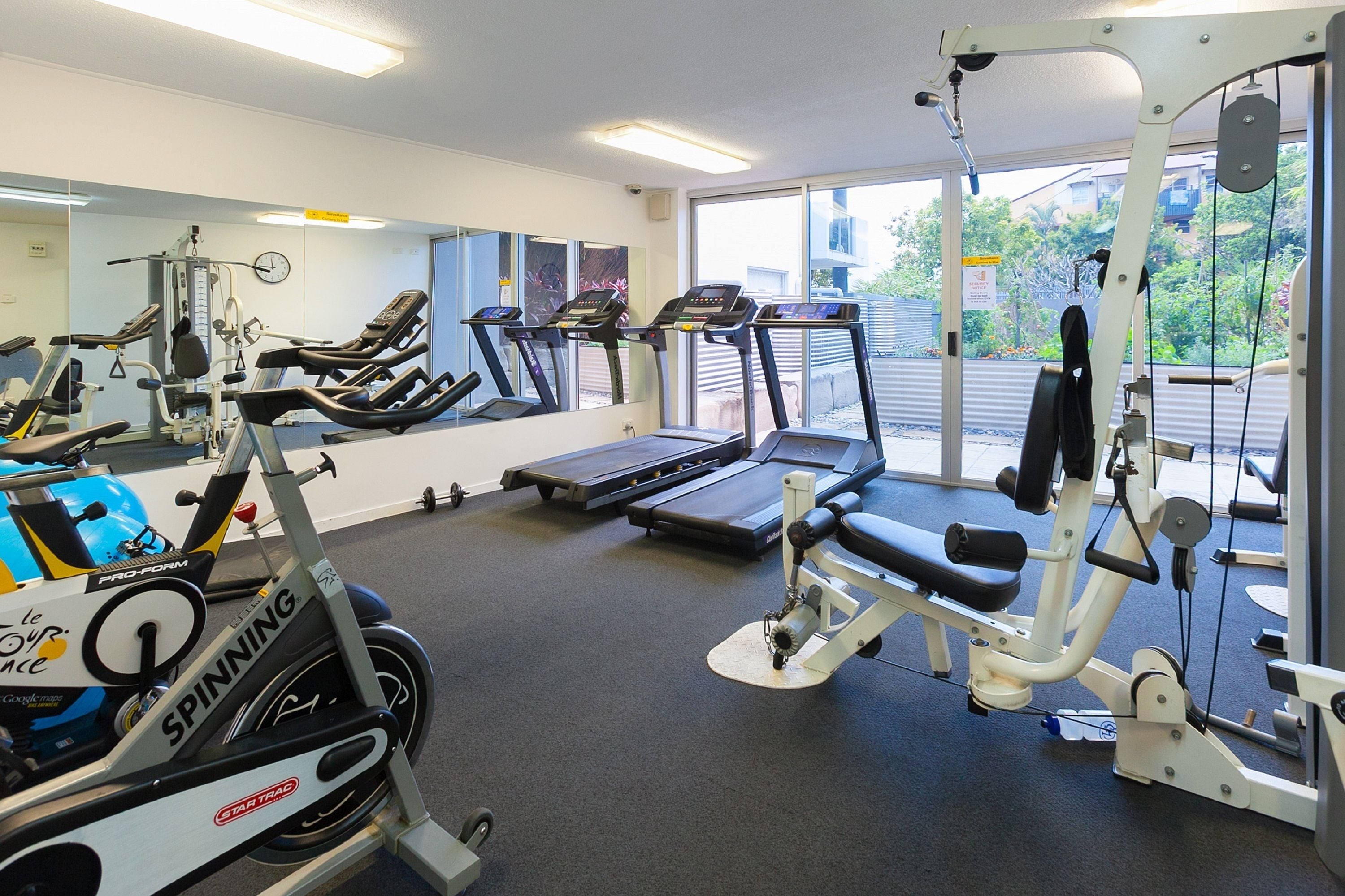 Une salle de sport équipée de tapis de course, de vélos elliptiques et de matériel de musculation.