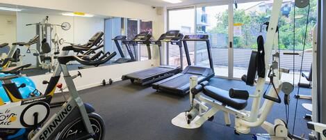 Une salle de sport équipée de tapis de course, de vélos elliptiques et de matériel de musculation.