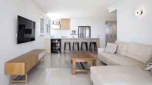 Una sala de estar moderna con una mesa de centro de madera, un sofá y un televisor instalado en la pared.