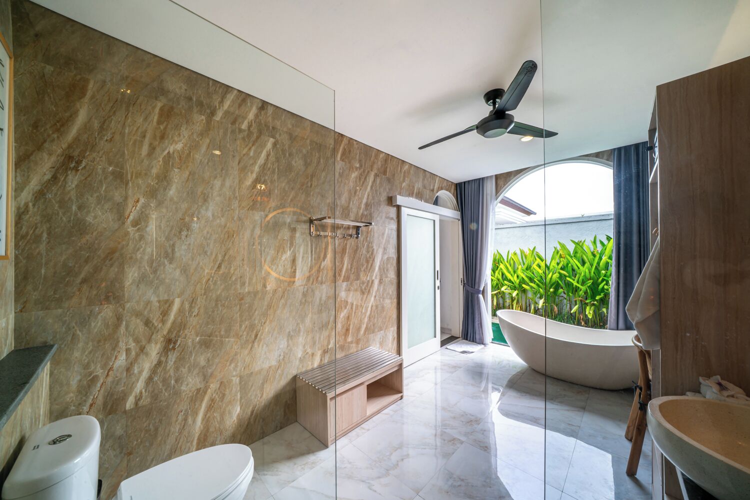 Een moderne badkamer met een vrijstaand bad, een douche en een toilet.