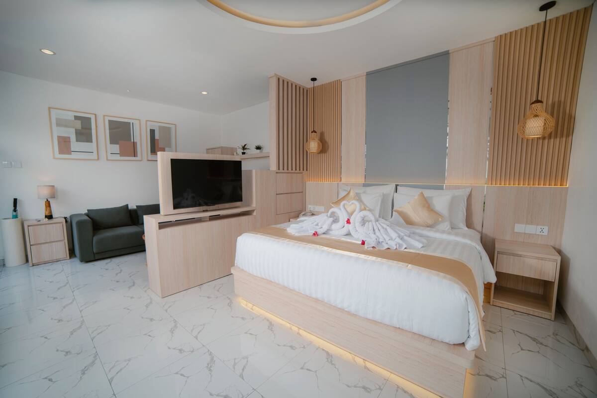 Ein modernes Schlafzimmer mit einem großen Bett, einem Fernseher und einer Couch.