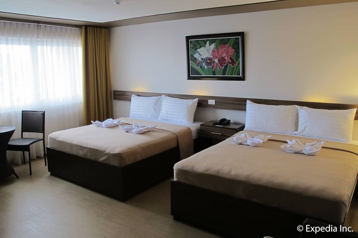 Habitación de hotel con dos camas, un escritorio, una silla y un cuadro en la pared.