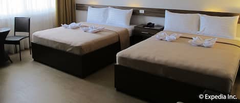 Habitación de hotel con dos camas, un escritorio, una silla y un cuadro en la pared.