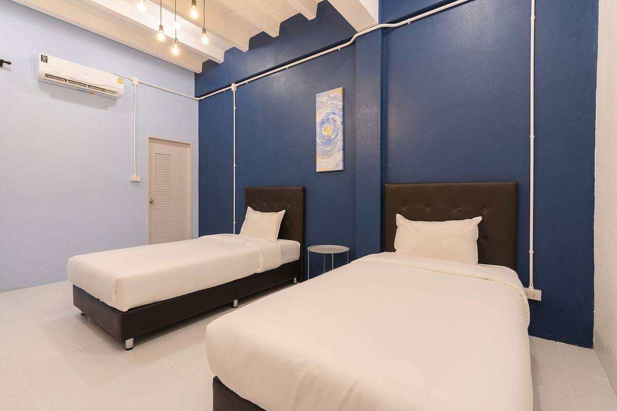 A room with two beds, a wall-mounted air conditioner, and a small round table.