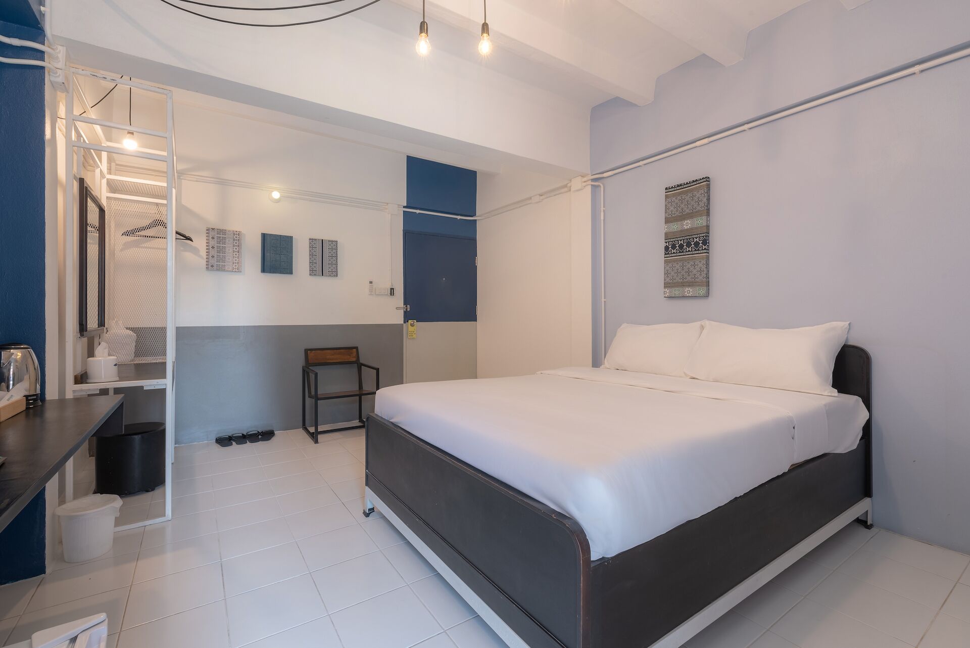 A modern bedroom with a bed, a chair, a desk, and a small table.