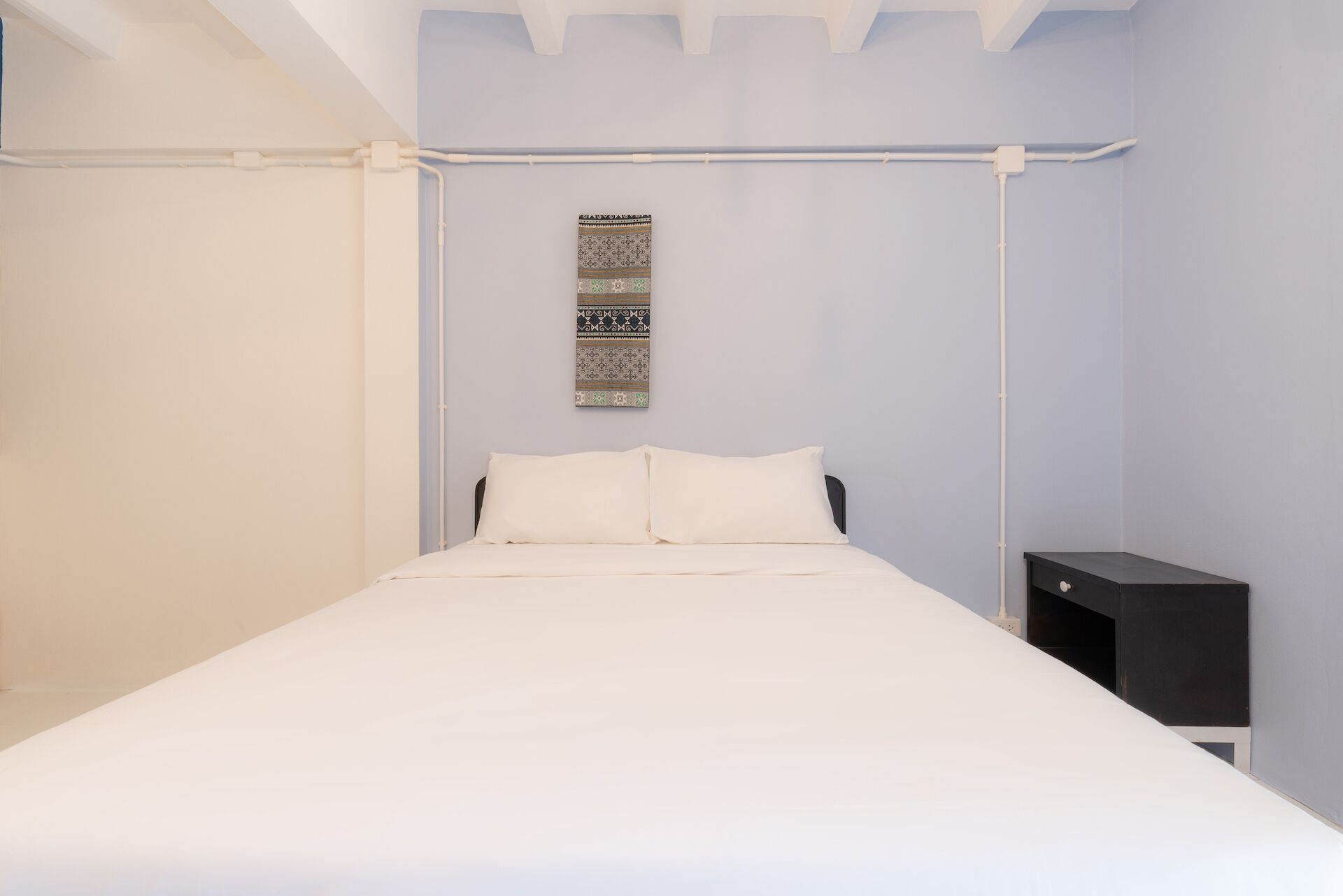 A bedroom with a bed, a nightstand, and a wall-mounted artwork.