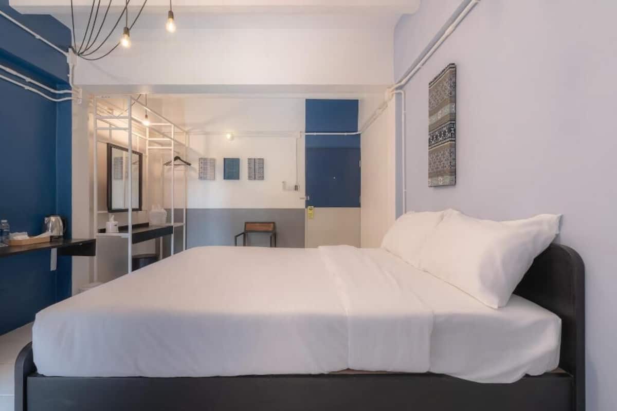 A modern hotel room with a large bed, a desk, and a mirror.