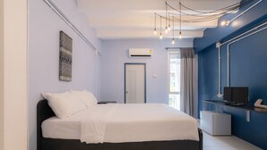 A modern bedroom with a bed, a TV, and a small desk. - BEDGASM Hotel x Café at Nimman (Chiang Mai)