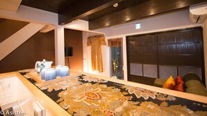 Hotelkamer met een groot bed, een klein tafeltje met een dienblad met kopjes en een theepot, een raam met gordijnen en uitzicht op buiten.