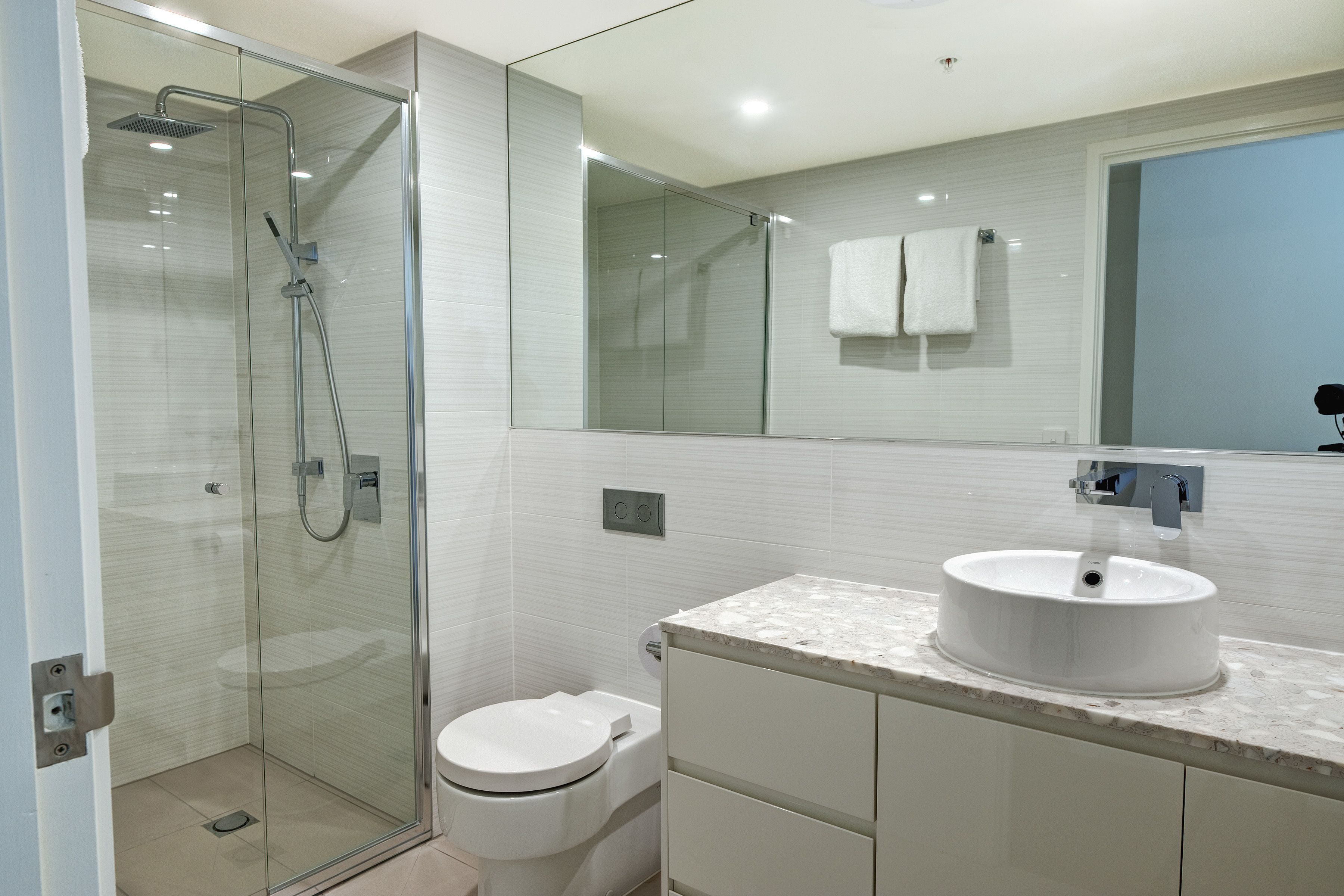 Ein modernes Badezimmer mit einer Duschkabine, einer weißen Toilette und einem мраморным Waschbecken.