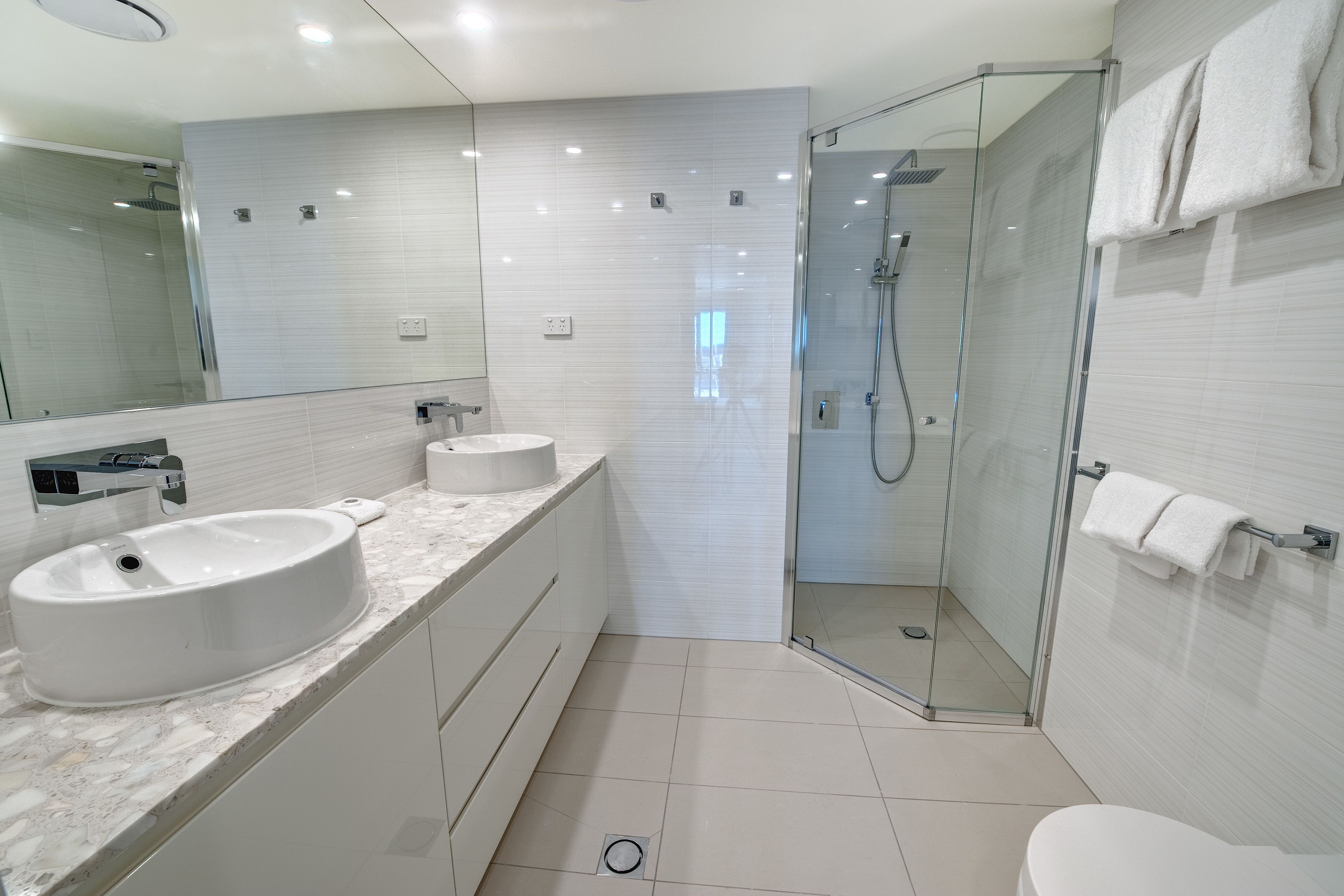 A modern bathroom with a glass-enclosed shower, a large sink, and a toilet.