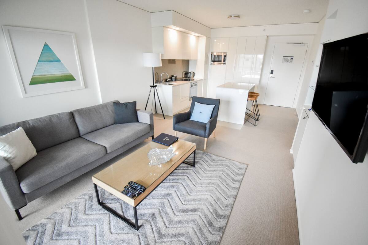 A modern living room with a grey sofa, a wooden coffee table, and a TV.