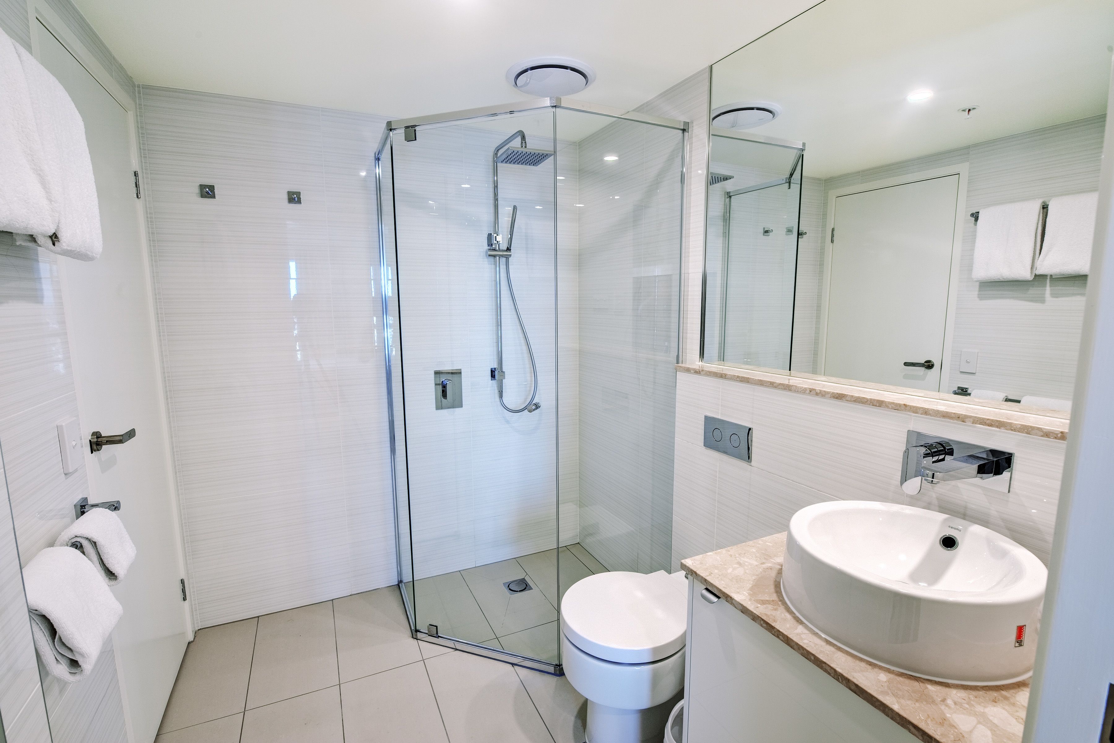 Ein modernes Badezimmer mit einer Duschkabine aus Glas, einem weißen Waschbecken und einer Toilette.