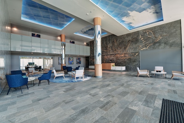 A spacious lobby with modern seating, a reception desk, and a large mural on the wall.