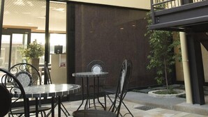 A multi-level outdoor patio with tables and chairs, a staircase, and a view of the building's interior. - Aoi Hotel (Nagoya)