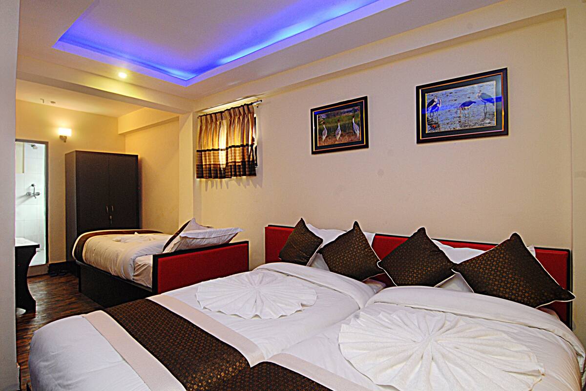 Habitación de hotel con dos camas, un armario y dos cuadros en la pared.