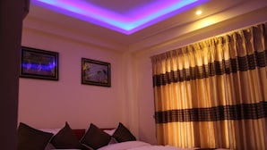 A hotel room with a bed, two framed pictures on the wall, and a curtain with a striped pattern. - Hotel Gallery Nepal (Kathmandu)