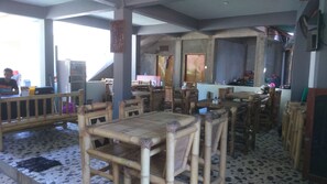 A restaurant with bamboo furniture, tiled flooring, and a bar area. - Family Garden Homestay (Senggigi)