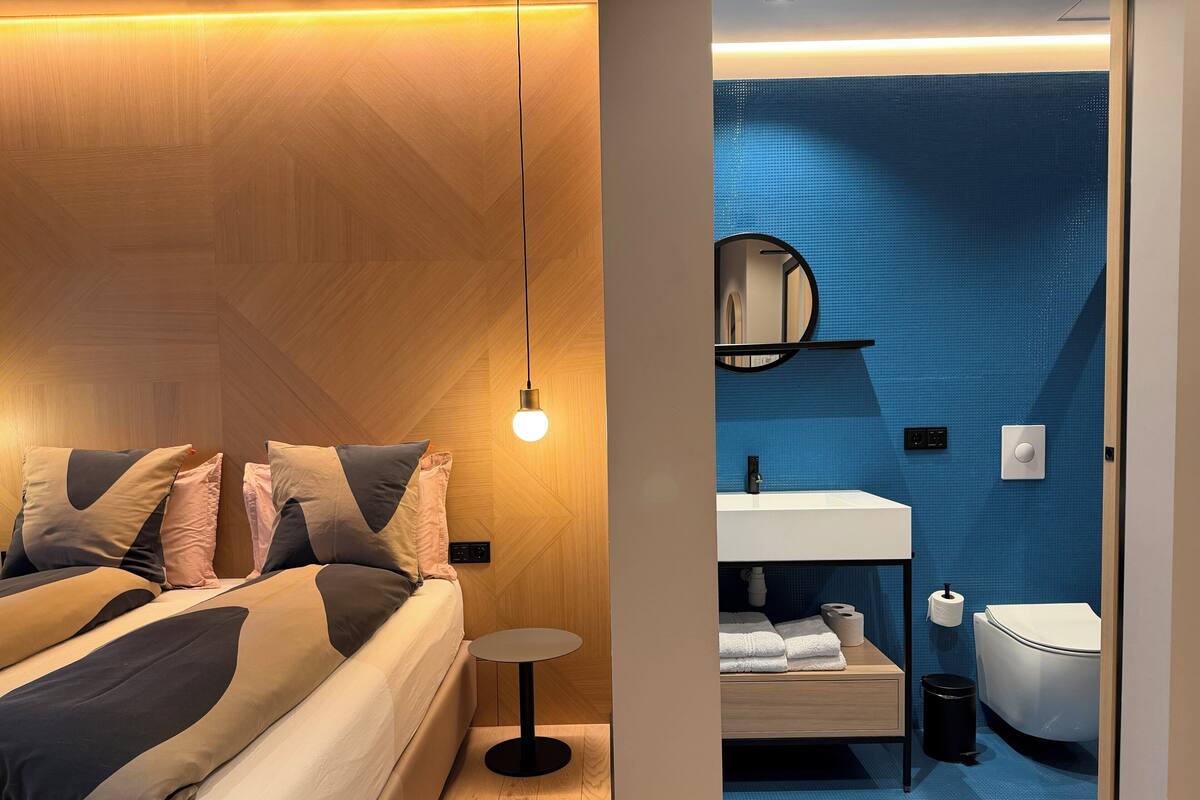 A modern bedroom with a bed, bedside table, and a hanging light fixture.