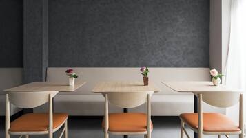 A modern interior with three wooden tables and matching chairs, a grey patterned wall, and a bench.