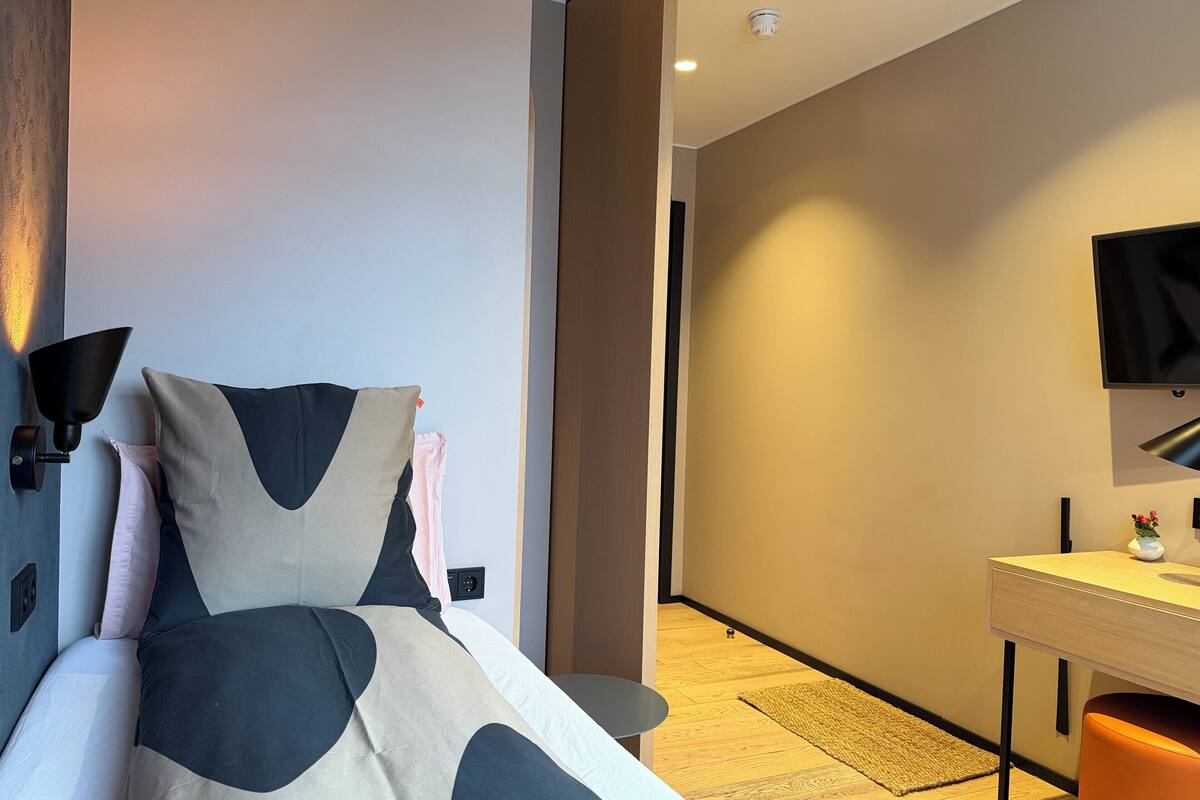 Una habitación de hotel moderna con una cama, un escritorio y una televisión.