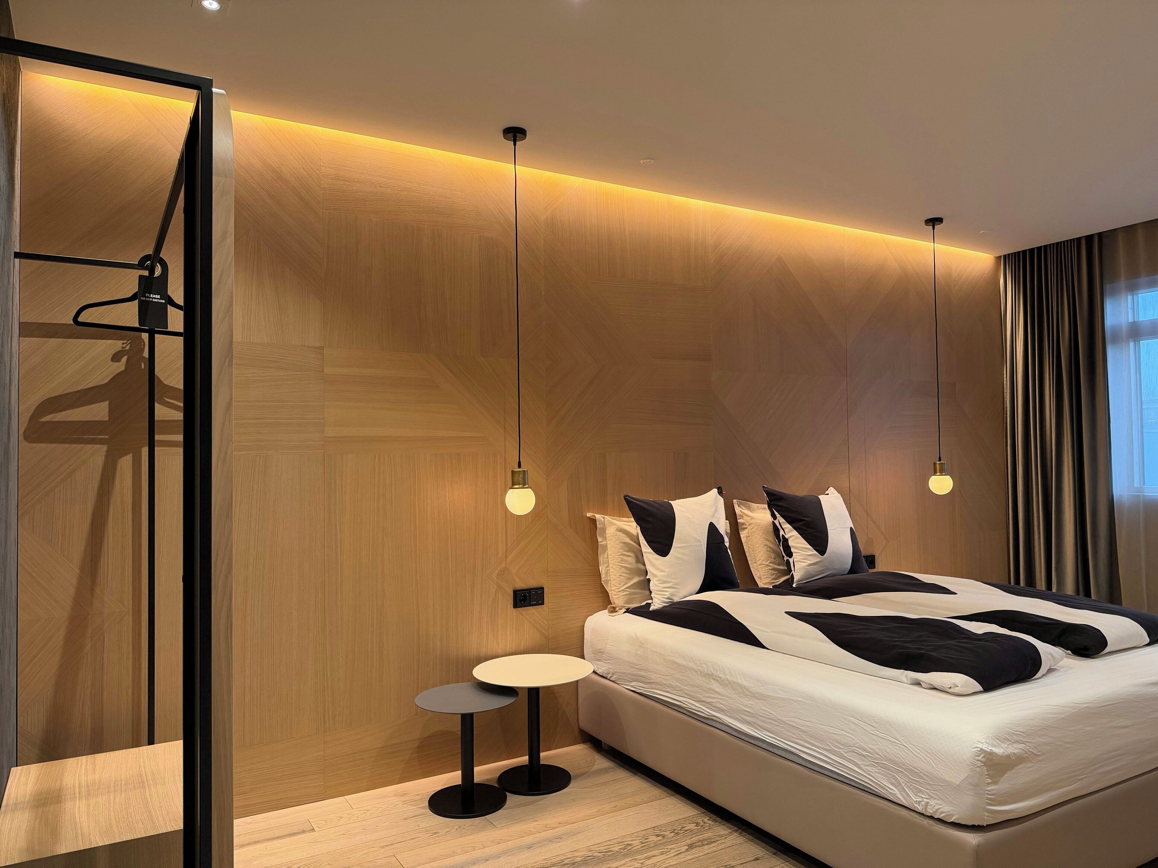 A modern bedroom with a bed, bedside tables, and pendant lighting.