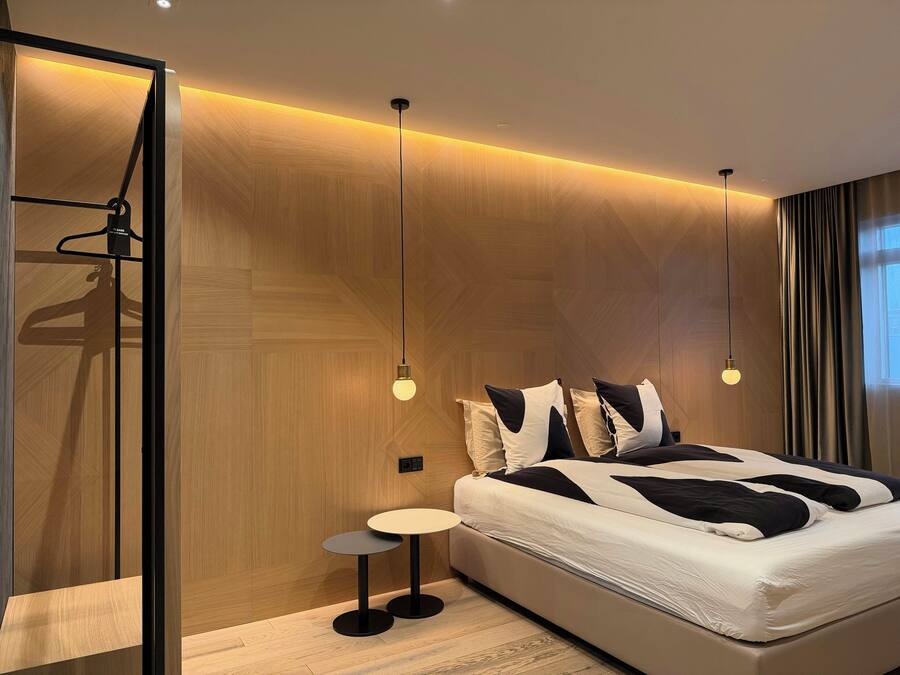 A modern bedroom with a bed, bedside tables, and pendant lighting.