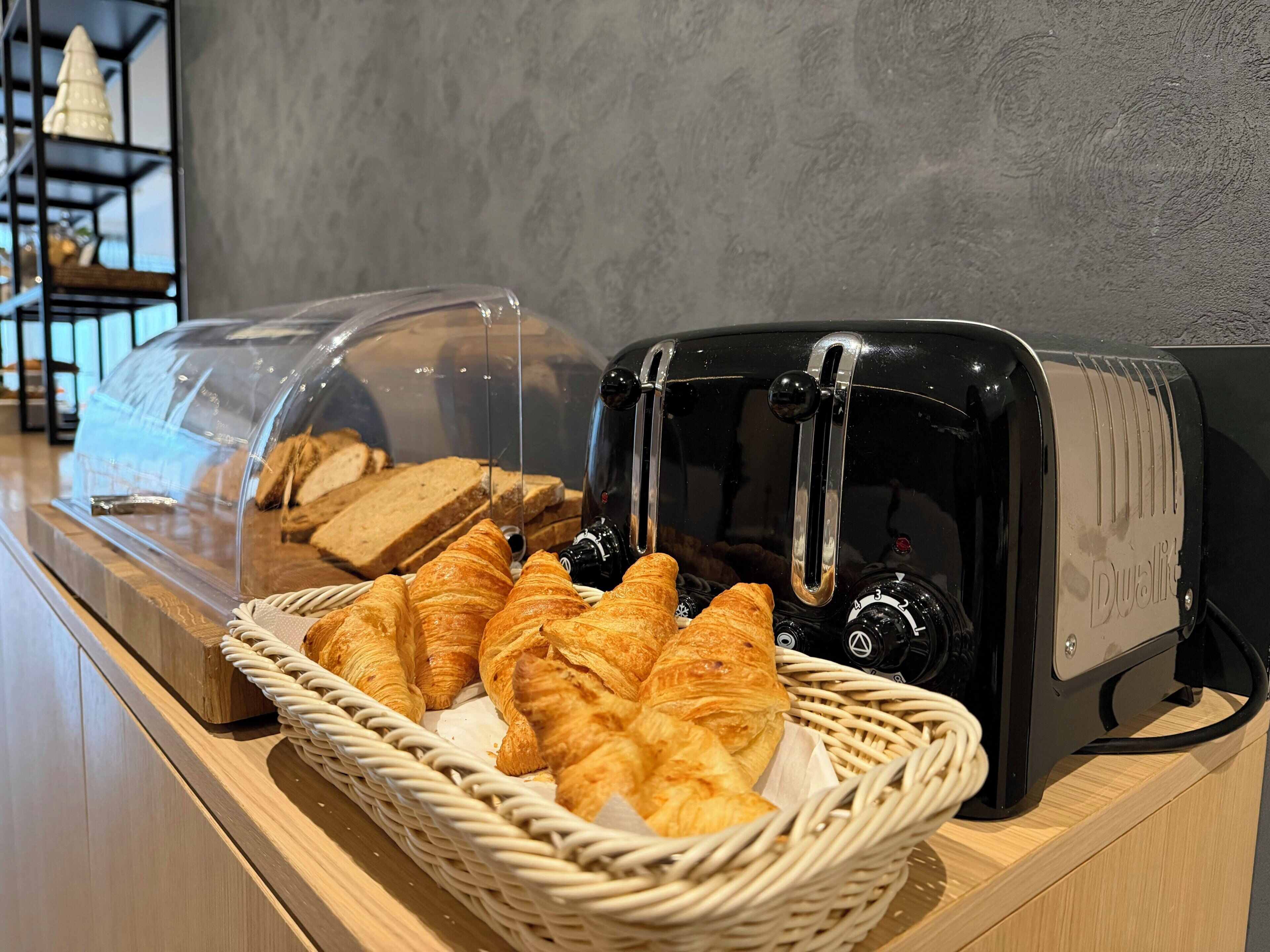 Un assortiment de produits pour le petit-déjeuner comprenant du pain, des croissants et un grille-pain.
