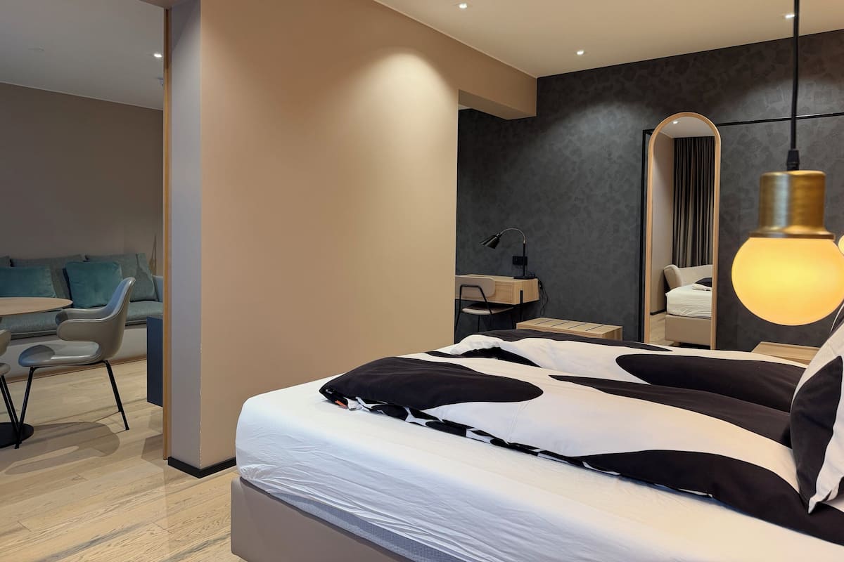 Un dormitorio moderno con cama, mesita de noche, lámpara y espejo.