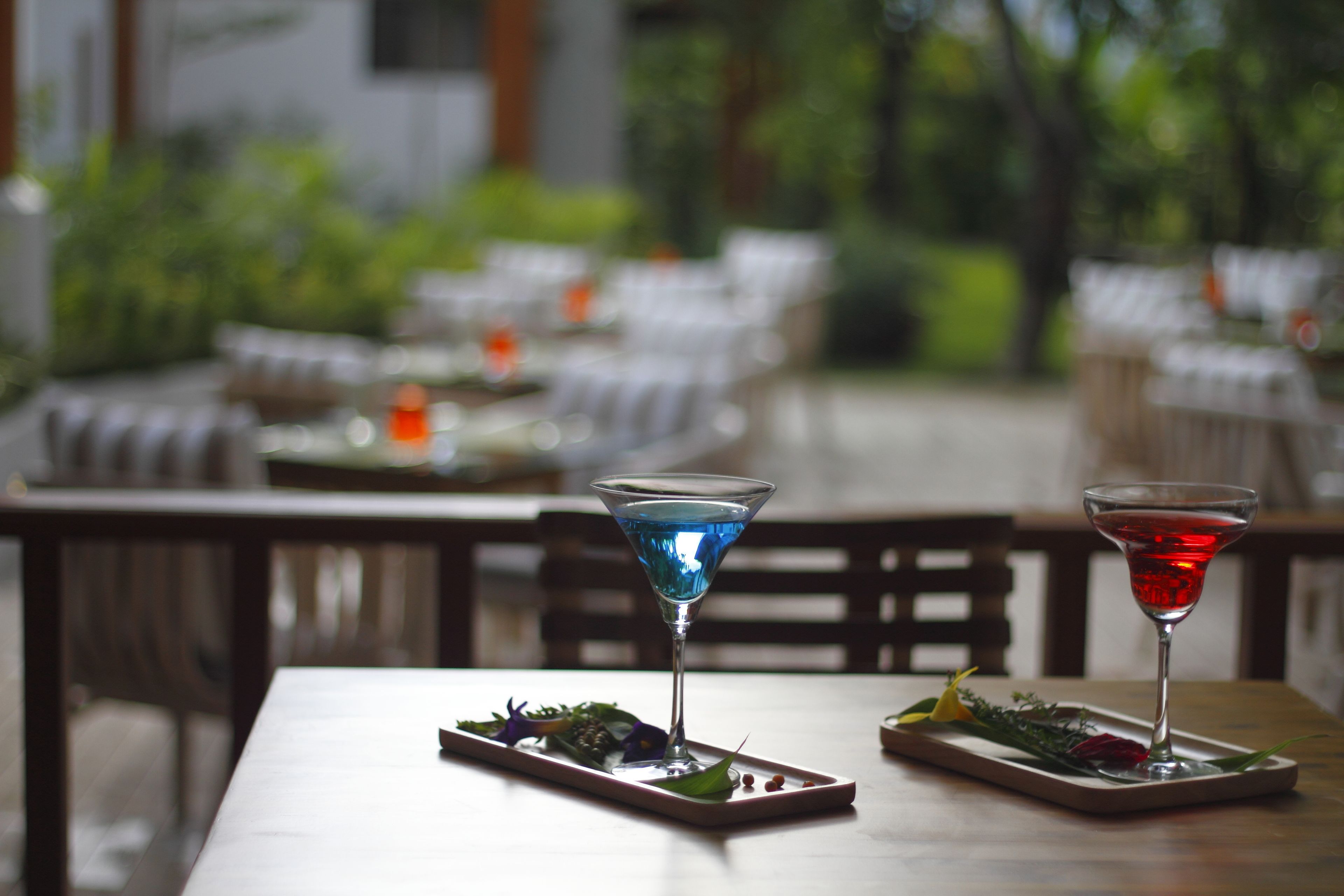 Ein Esstisch mit zwei Martini-Gläsern, jedes gefüllt mit einem farblich unterschiedlichen Getränk, und einer kleinen Speisenplatte.