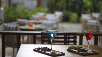 Ein Esstisch mit zwei Martini-Gläsern, jedes gefüllt mit einem farblich unterschiedlichen Getränk, und einer kleinen Speisenplatte.