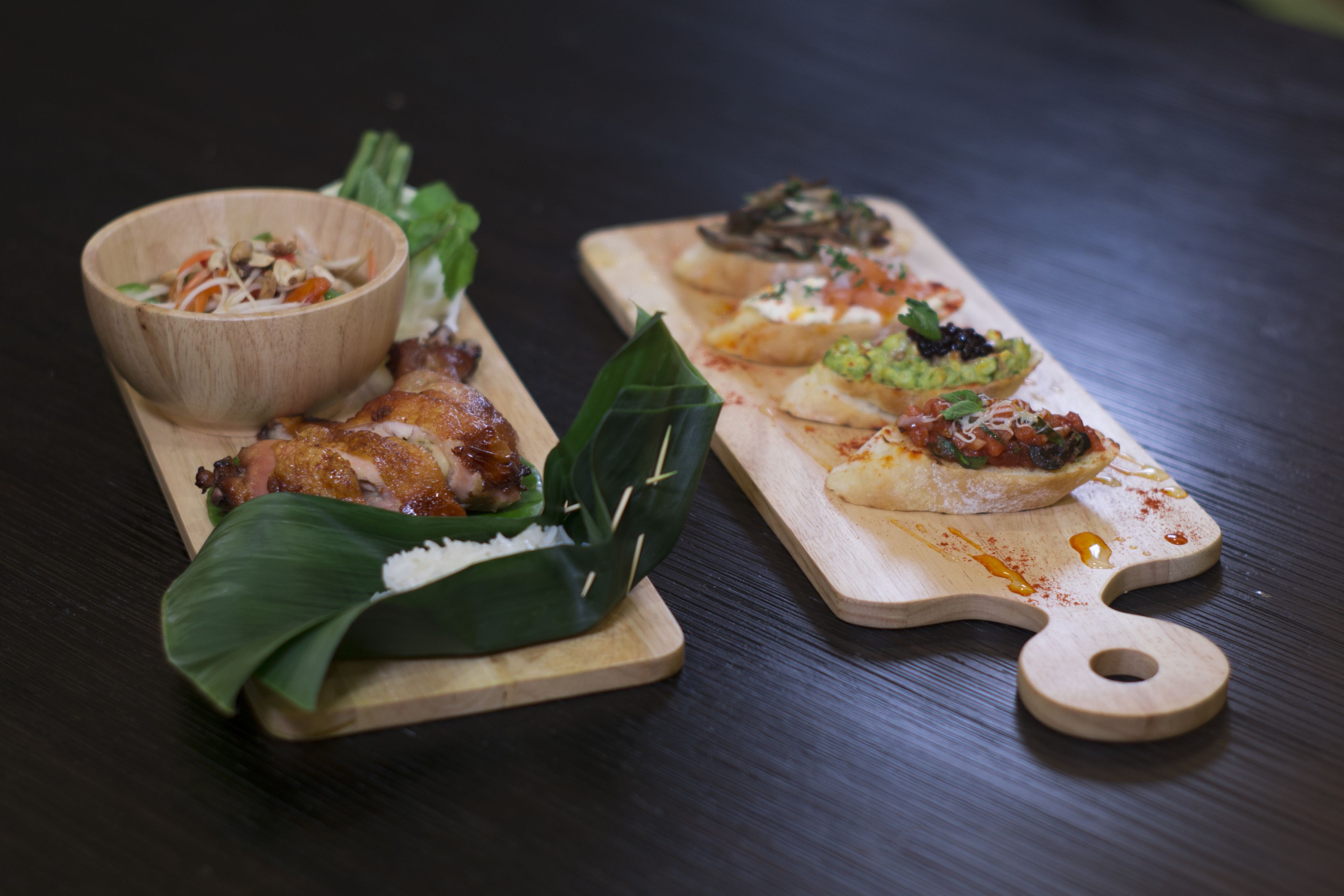 Una tabla de madera con diversos platos, incluyendo un bol de ensalada y un plato con diferentes alimentos.