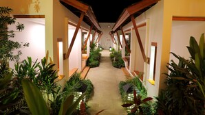 A corridor with wooden beams and potted plants, leading to a central area with a light source. - Mount Inle Hotel & Resorts (Nyaungshwe)