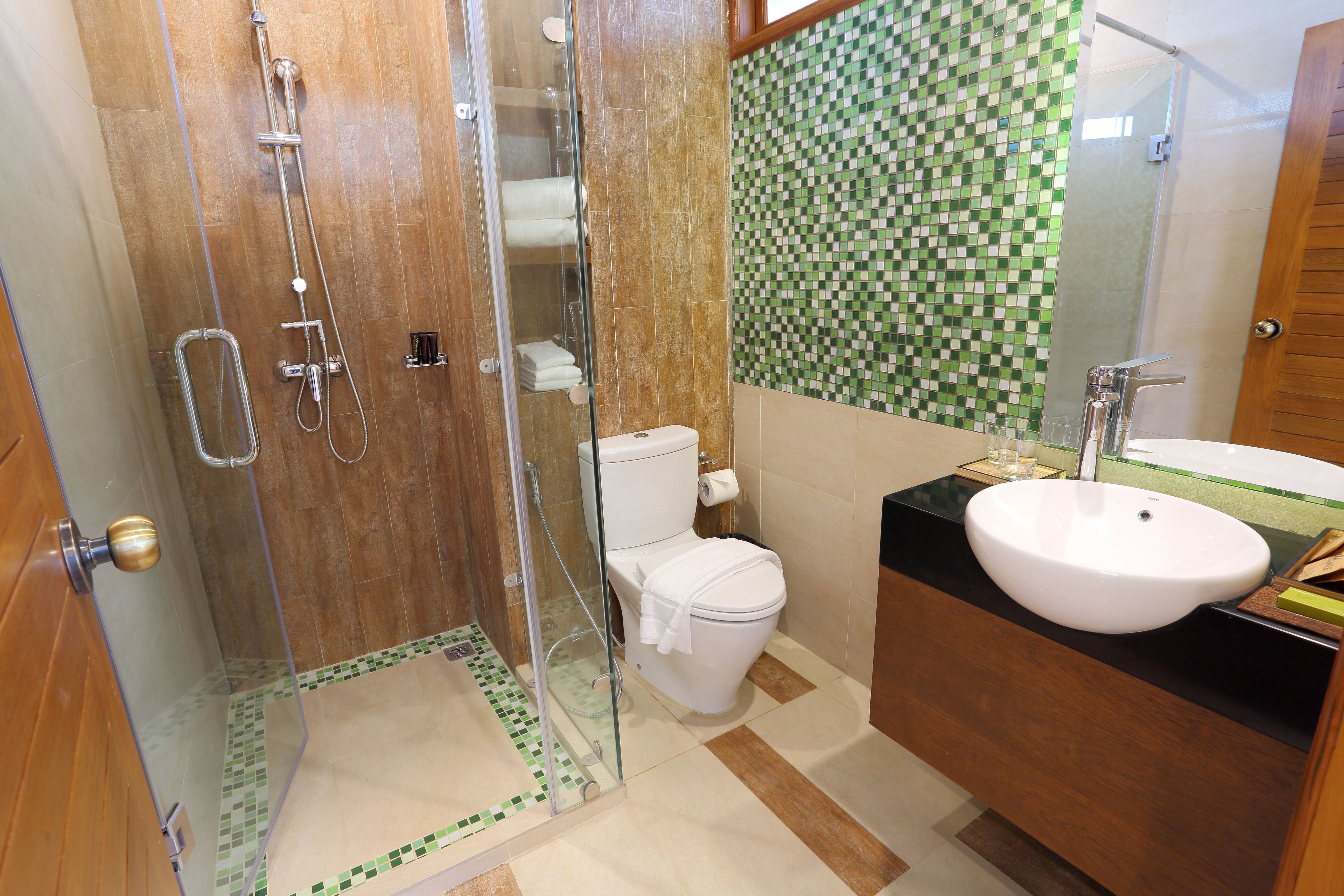 Un baño con ducha de vidrio, inodoro y lavamanos con espejo.