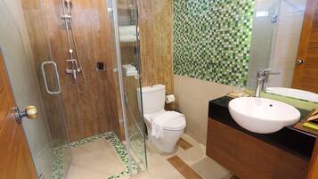 Un baño con ducha de vidrio, inodoro y lavamanos con espejo.