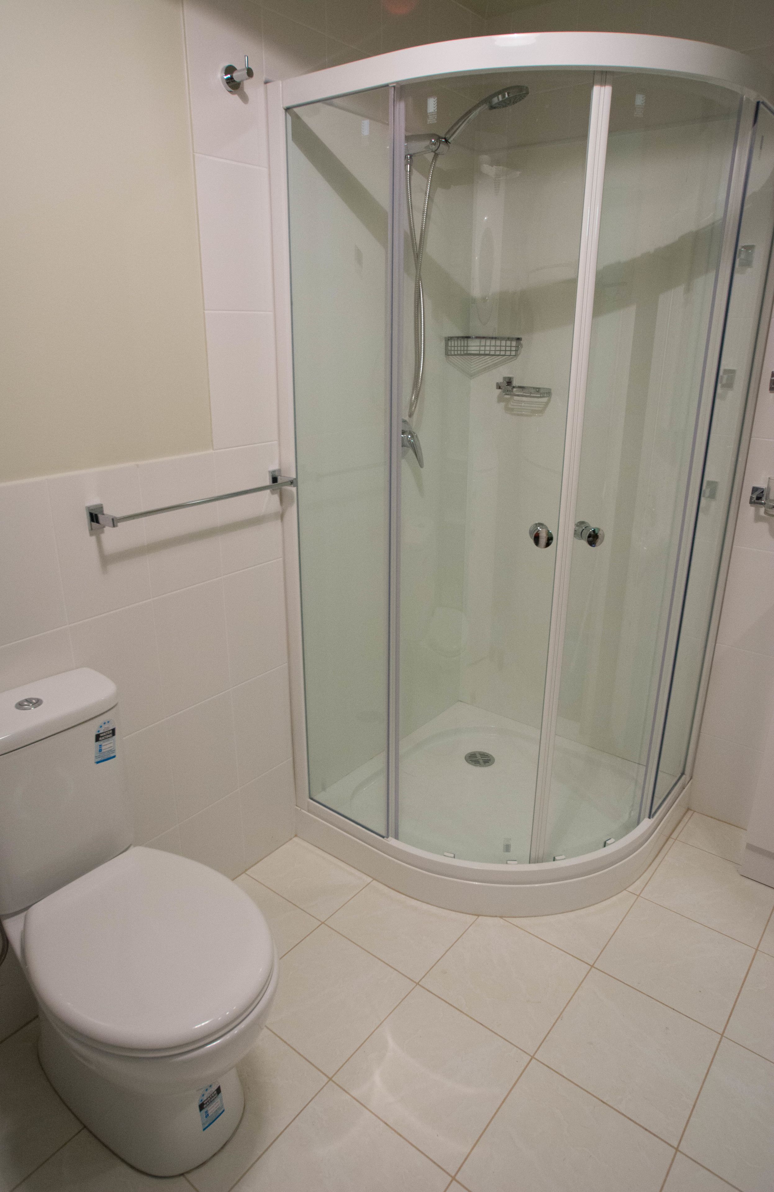 A modern bathroom with a glass-enclosed shower, a toilet, and a glass shower door.