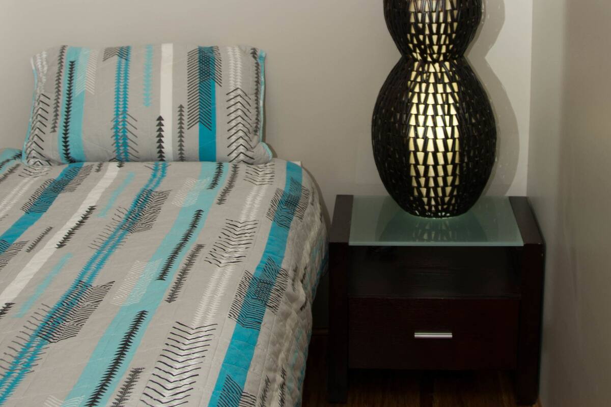 A bedroom with a bed, a nightstand, a decorative lamp, and a wall calendar.