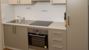 A modern kitchen with stainless steel appliances, a sink, and cabinets. - Westside Studio Apartments (Armidale)