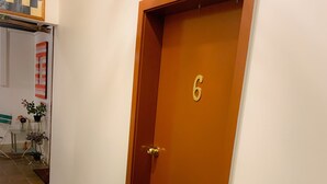 A wooden door with the number 6, a stone-tiled floor, and a wall with a framed picture. - Westside Studio Apartments (Armidale)