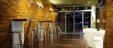A modern lobby with wooden walls, a reception desk, and a seating area with bar stools.